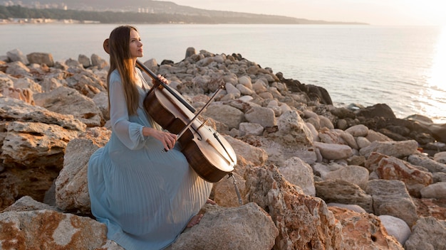 Foto gratuita músico tocando el violonchelo al atardecer