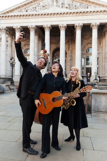 Foto gratuita músicos de tiro completo tomando selfie al aire libre