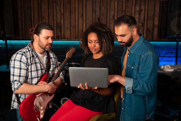 Músicos de tiro medio trabajando con laptop