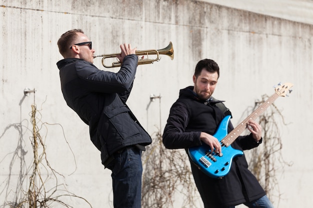 Músicos tocando en frente de un muro de cemento