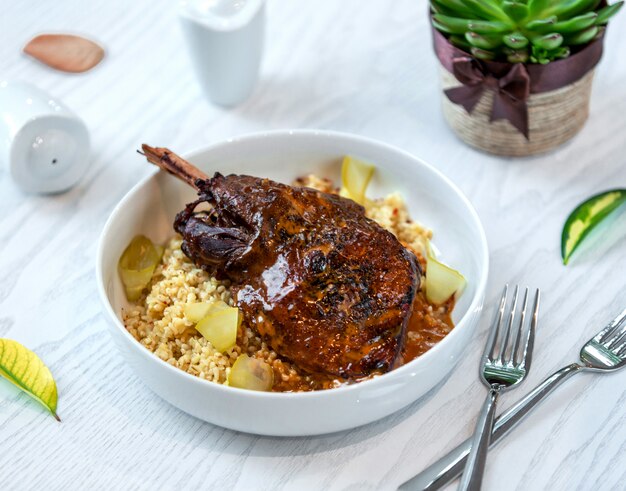 Muslo de pollo asado con salsa servido en bulgur con pepinillos