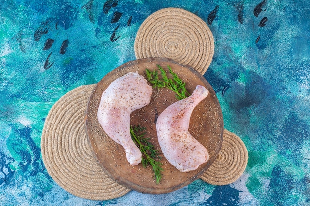 Foto gratuita muslo de pollo marinado con eneldo sobre una tabla sobre un salvamanteles