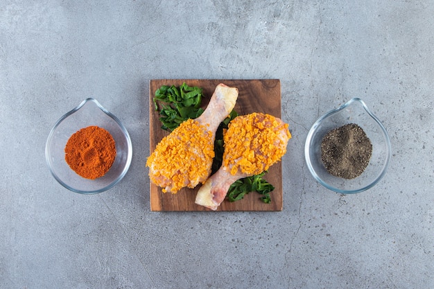 Muslo de pollo marinado en un verde sobre una tabla, sobre la superficie de mármol.