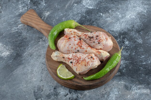 Muslo de pollo picante crudo sobre una tabla de cortar de madera