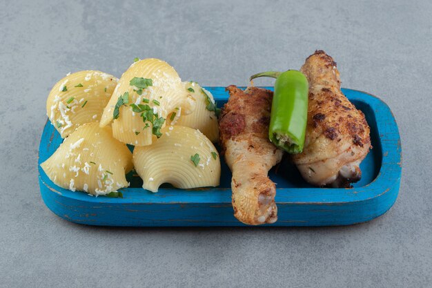 Muslos a la plancha y pasta de conchas en placa azul.