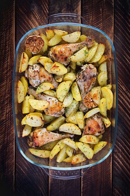 Muslos de pollo al horno con patatas en rodajas y hierbas. Muslos de pollo a la barbacoa. Vista superior, arriba, copie el espacio.