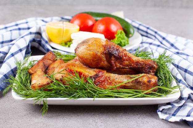 Muslos de pollo al horno con verduras en una placa blanca.