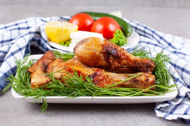 Muslos de pollo al horno con verduras en una placa blanca.