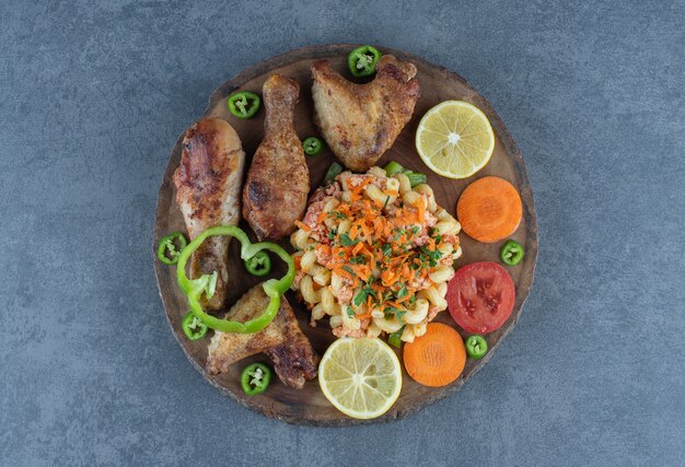 Muslos de pollo asado y pasta sobre pieza de madera.