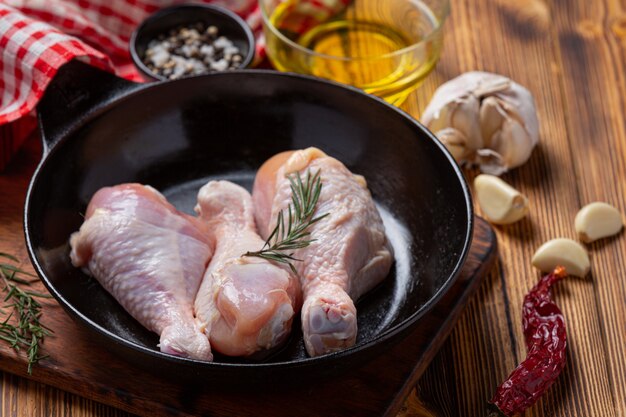 Muslos de pollo crudo crudo sobre la superficie de madera oscura.