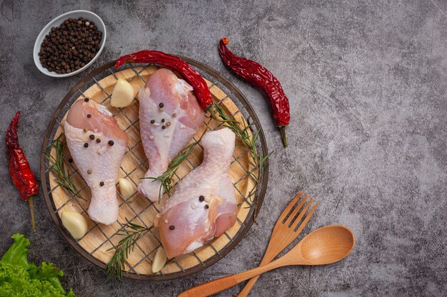 Muslos de pollo crudo crudo sobre la superficie oscura.