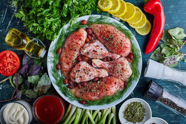 Muslos de pollo crudo y filete en una placa verde.