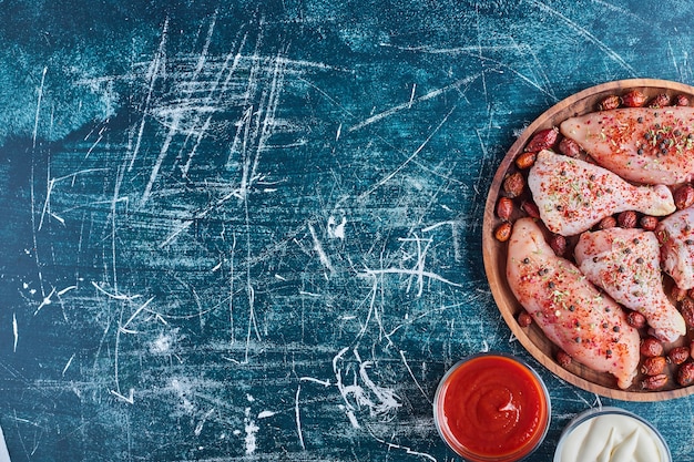 Foto gratuita muslos de pollo crudo y filete en un plato de madera.