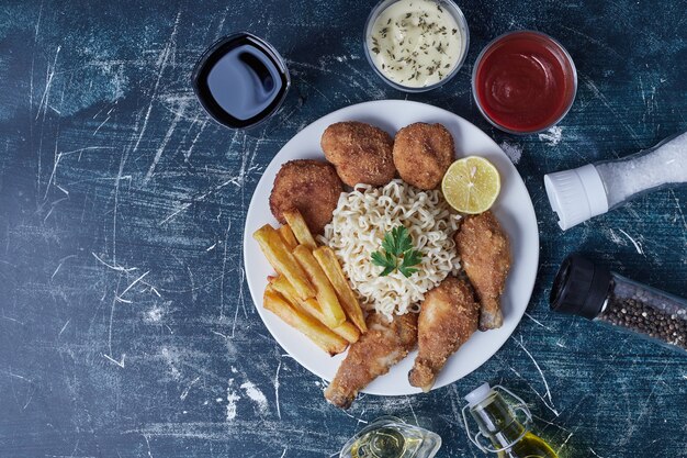 Muslos de pollo crujientes con palitos de patata y salsas.