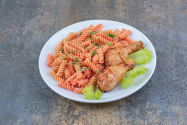 Muslos de pollo deliciosos y macarrones en un plato blanco. Foto de alta calidad