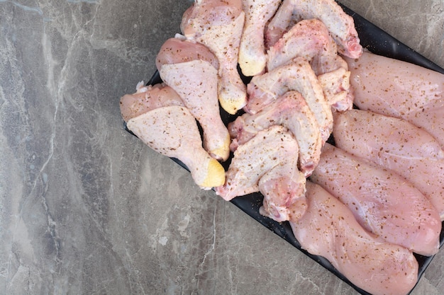 Foto gratuita muslos de pollo frescos sin preparar en un plato oscuro. foto de alta calidad