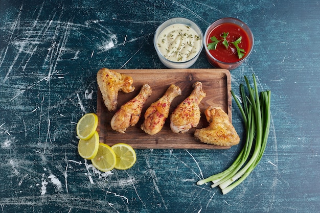 Muslos de pollo frito con limón y cebolla sobre una tabla de madera.