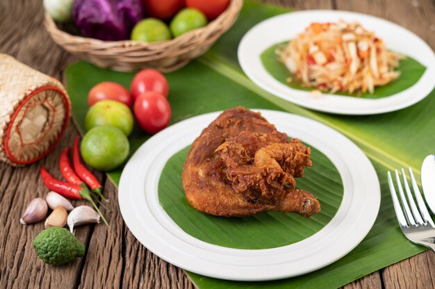 Muslos de pollo fritos en hojas de plátano en un plato blanco