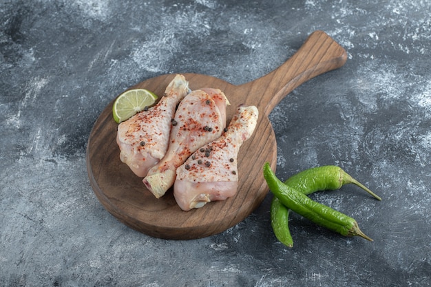 Foto gratuita muslos de pollo orgánicos frescos sobre una tabla de cortar de madera.