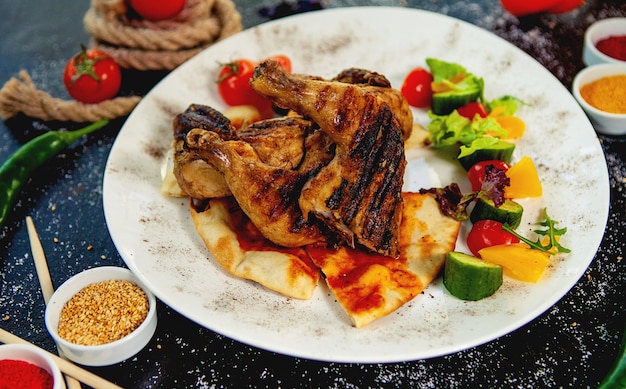 Muslos de pollo a la parrilla sobre pan de pita servidos con vegetales frescos