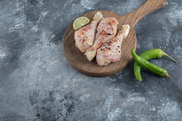 Muslos de pollo picantes y pimientos sobre fondo gris.