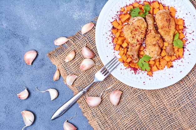 Muslos de pollo con verduras en un plato blanco.