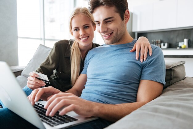 Muy guapo hombre y mujer usando la computadora portátil