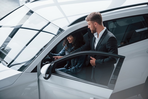 Muy interesante. Clienta y empresario barbudo con estilo moderno en el salón del automóvil