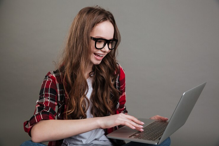 Foto gratuito muy sonriente jovencita chateando por computadora portátil