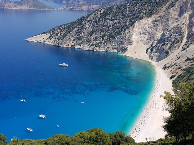 Foto gratuita myrtos beach rodeada por el mar bajo la luz del sol en grecia