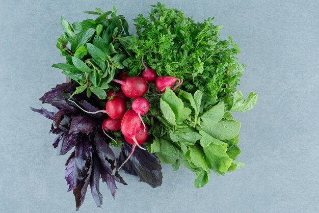 Nabos rojos, albahaca y menta sobre mármol.