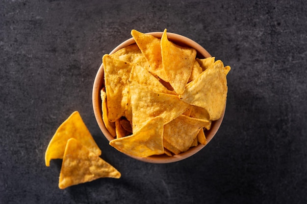 Nachos en cuenco de madera sobre fondo de pizarra negra