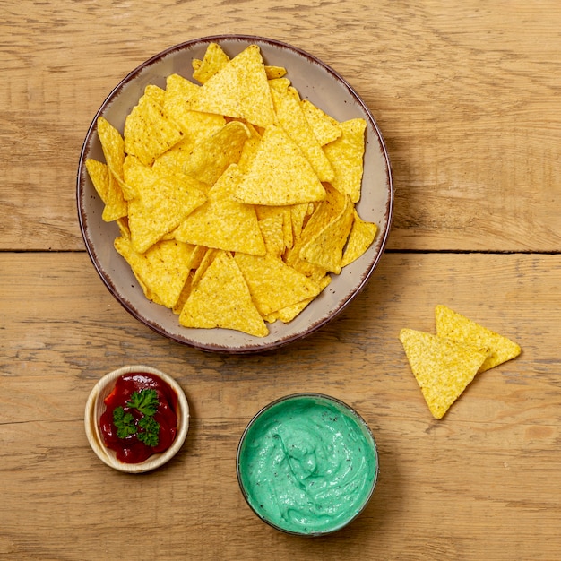 Nachos en plato y varias salsas en mesa de madera