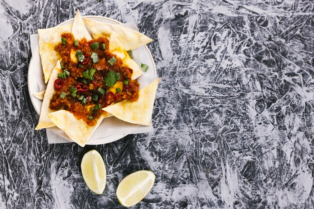 Nachos y rodajas de limón sobre superficie de mármol.