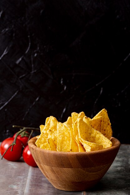 Nachos sabrosos en tazón de madera y tomates