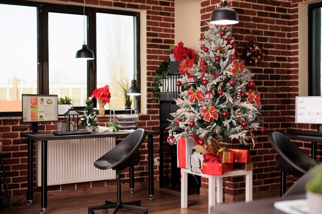 Nadie en la oficina de negocios con adornos de árboles de Navidad, decoración festiva y luces para celebrar la temporada de invierno en el trabajo de inicio. No hay personas en el lugar de trabajo de la empresa llenas de adornos navideños.