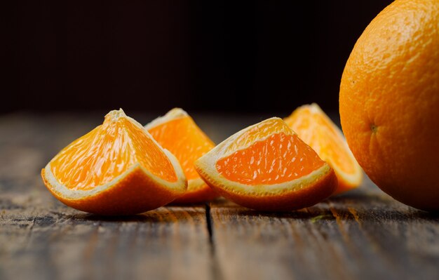 Naranja de buen gusto con vista lateral de rodajas en la mesa negra y de madera