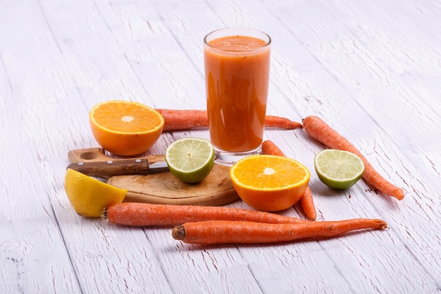 Naranja detox coctail con naranjas, limón y zanahorias se encuentra en la mesa blanca