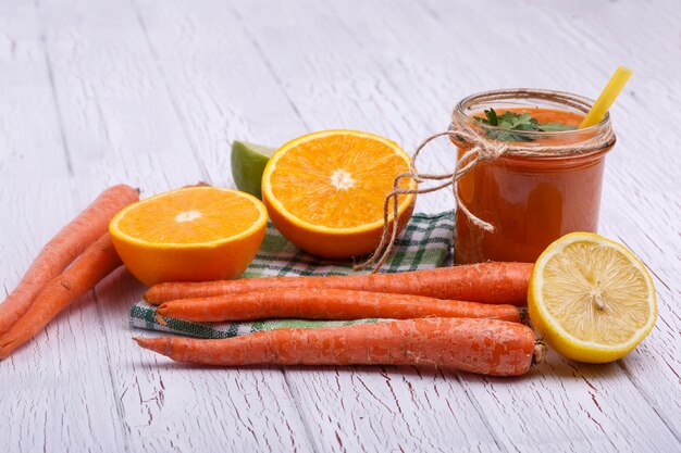 Naranja detox coctail con naranjas y zanahorias se encuentra en la mesa blanca