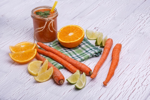 Naranja detox coctail con naranjas y zanahorias se encuentra en la mesa blanca