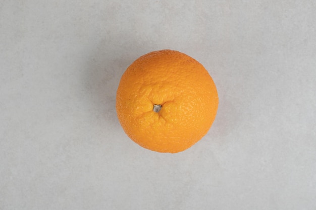 Naranja entera fresca sobre superficie gris.