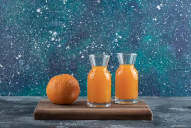 Naranja entera y jugo sobre tabla de madera.