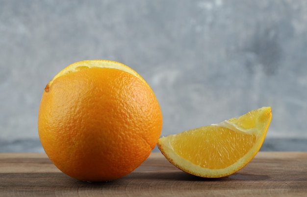 Naranja entera y en rodajas sobre mesa de mármol.