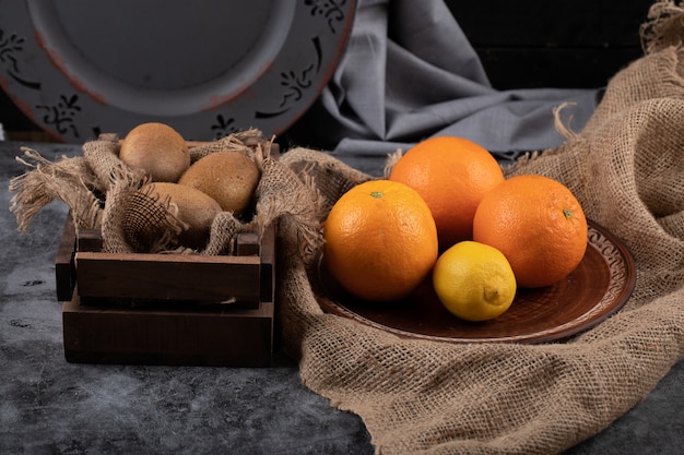 Naranja y kiwies en un oscuro espacio rústico.