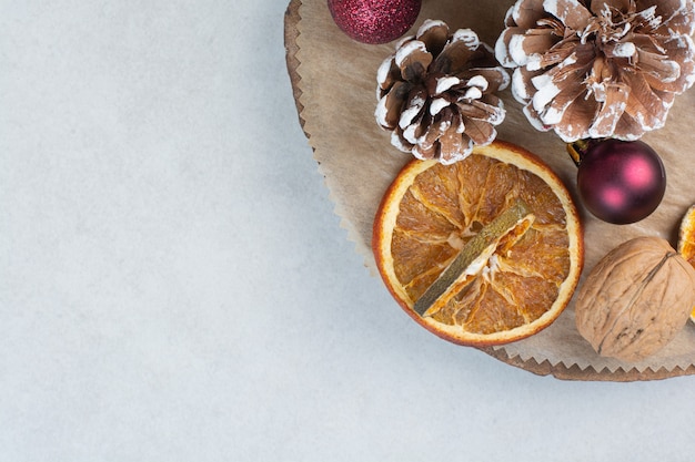 Naranja seca con piñas y bolas de Navidad en placa de madera. Foto de alta calidad