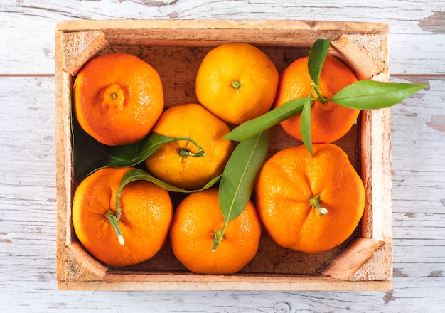 Naranjas en caja de madera vista superior en mesa de madera blanca