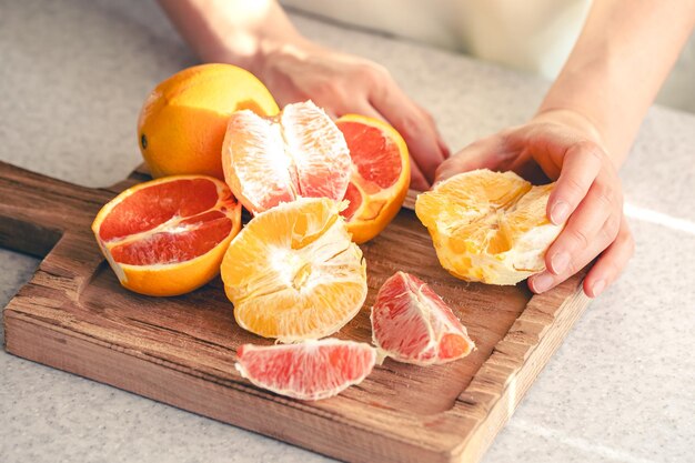 Naranjas descascaradas en manos femeninas y en una tabla de cortar de madera para el jugo