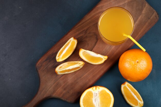 Naranjas enteras y en rodajas con un vaso de jugo. Vista superior.