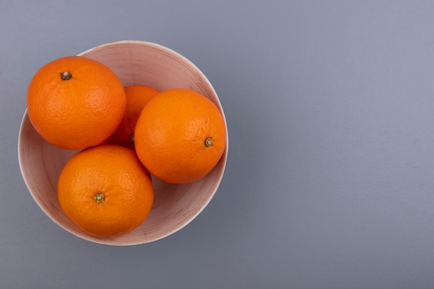 Naranjas de espacio de copia de vista superior en un tazón sobre fondo gris