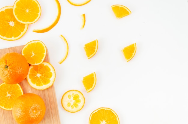 Naranjas esparcidas sobre tabla de cortar y mesa